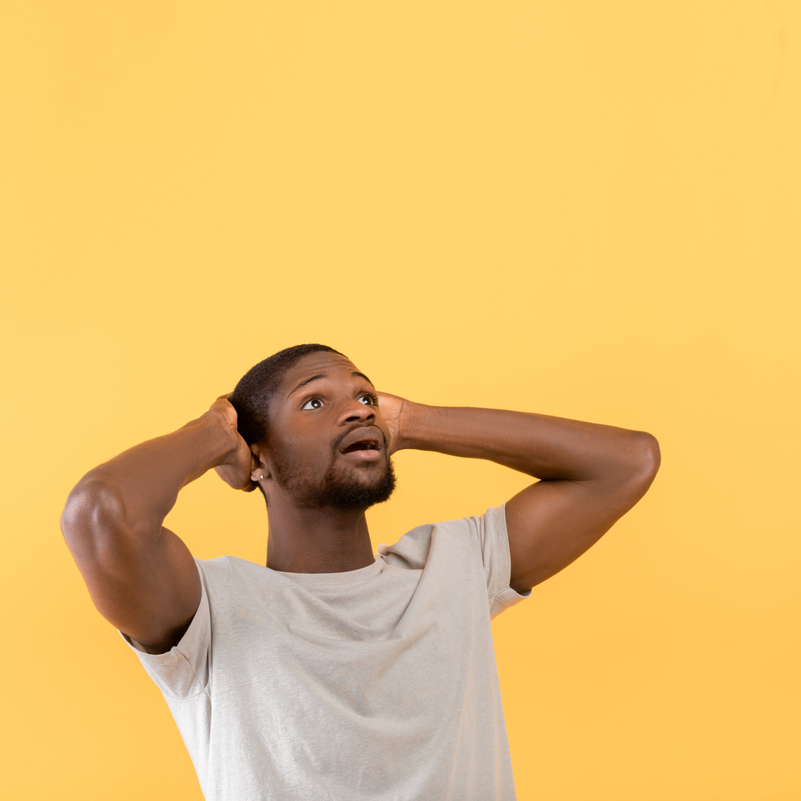 Shocking Offer. Emotional Black Guy Looking up at Free Space with Open Mouth, Standing over Yellow Background